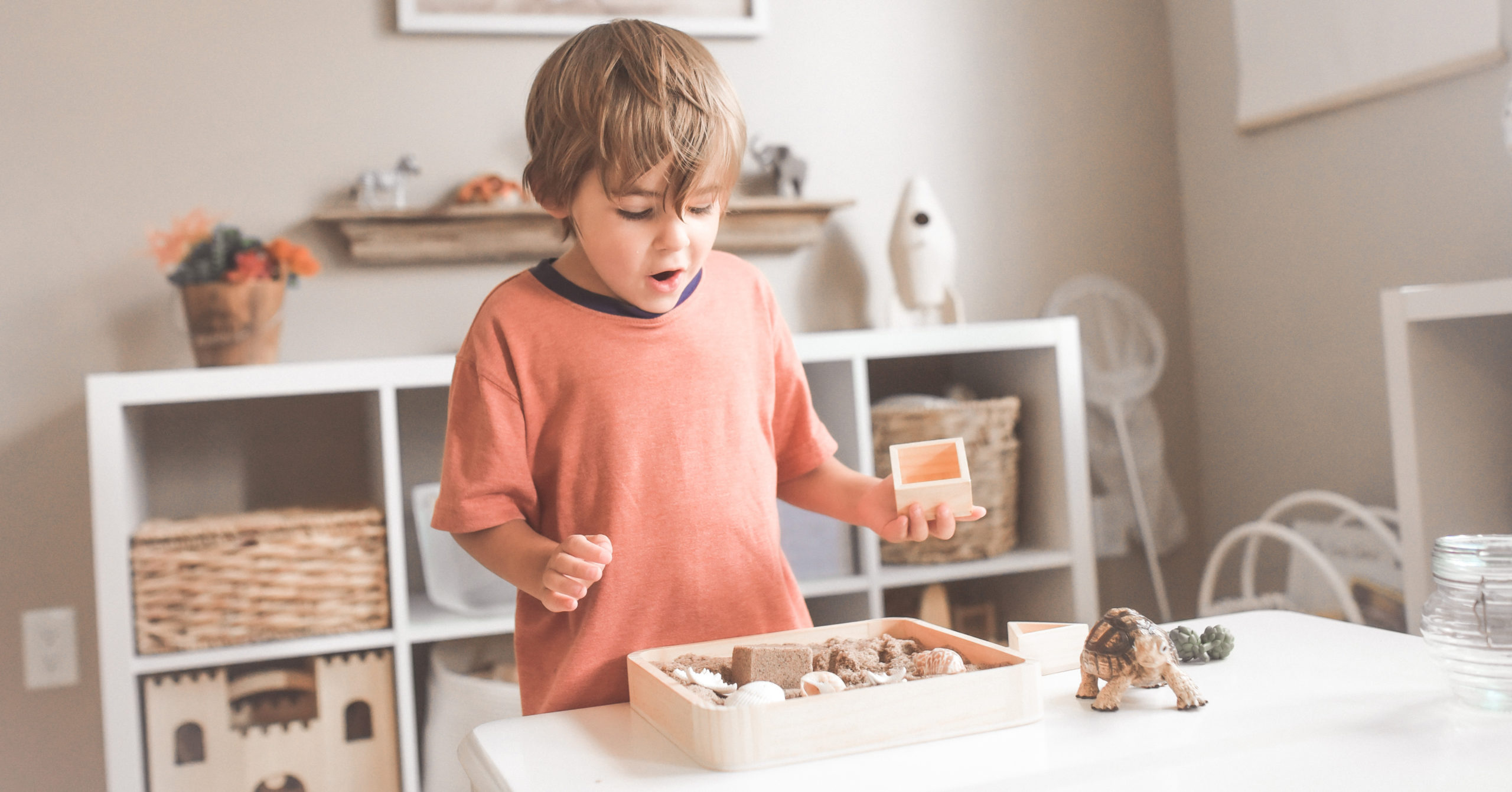 child playing with wooden toys and sand