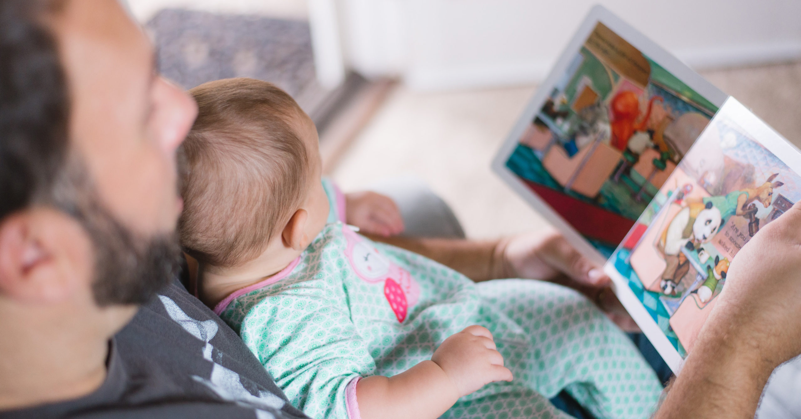 parent reading a board book to their baby